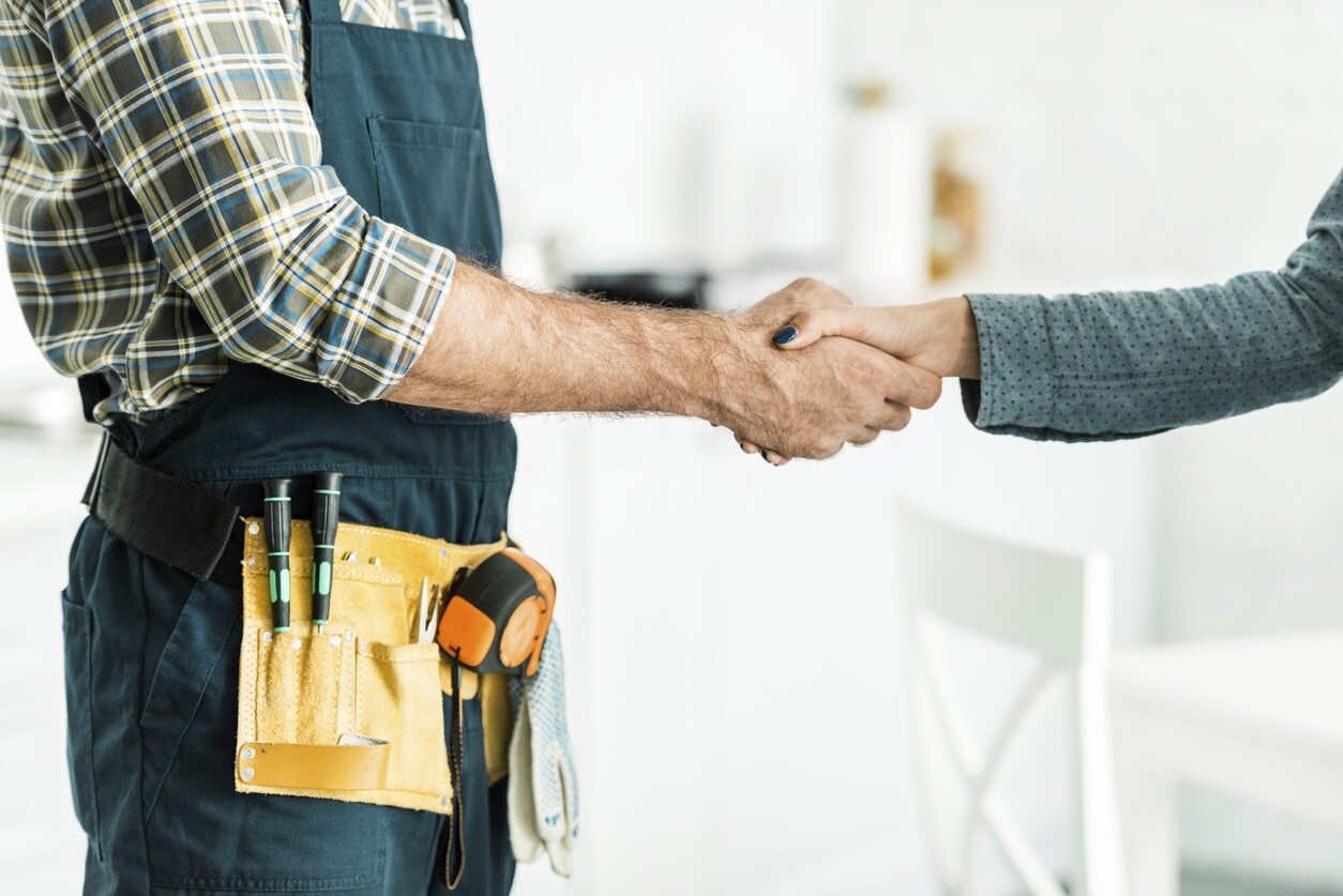 A male plumber shakes the hand of a female homeowner